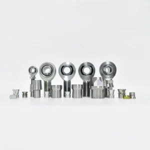 A collection of heim joints with accessories including tube adapters, jam nuts, spacers, and related components, arranged in a row.